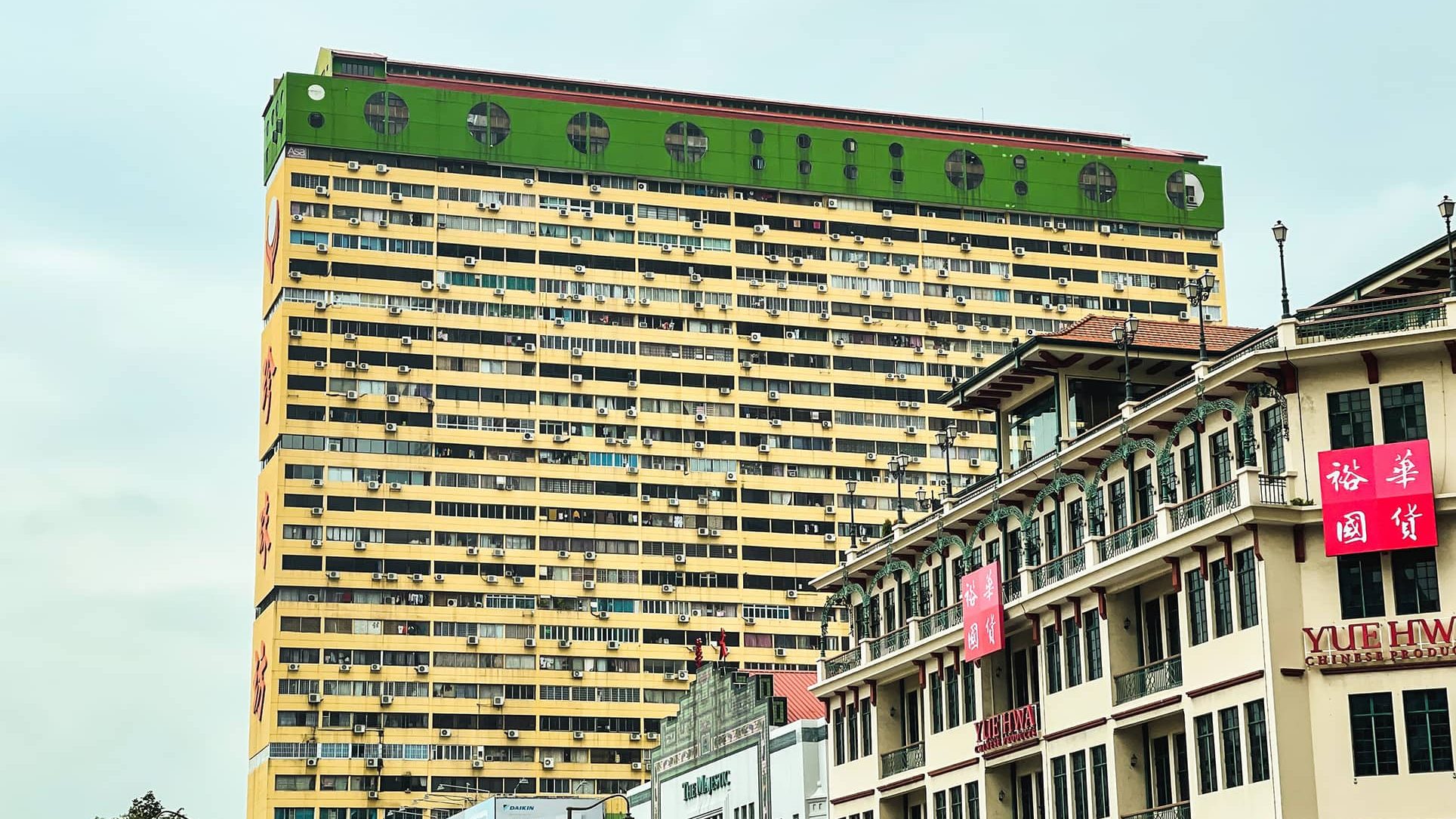 Yue Hwa Chinese products store in a heritage building with a tall yellow and green residential block behind it