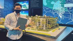 Man wearing a mask holding brochures next to a scaled architectural model and location map of Jervois Mansion apartments