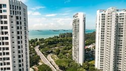 Amber Skye apartment blocks with a road winding through green trees and ships visible offshore under a blue sky