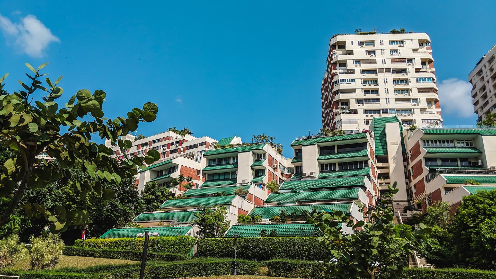 Pandan Valley residential blocks with green roofs surrounded by trees under a clear blue sky