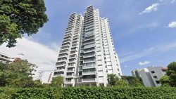 High-rise white residential apartment blocks surrounded by greenery and trees under a blue sky