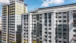 Housing blocks with clothes hanging outside windows under a partly cloudy blue sky