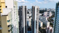 Tall residential blocks with a cityscape and green areas in the background under a blue sky