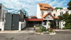 Two-storey terrace house with orange tiled roof next to a construction site with metal gates and blue tarpaulin