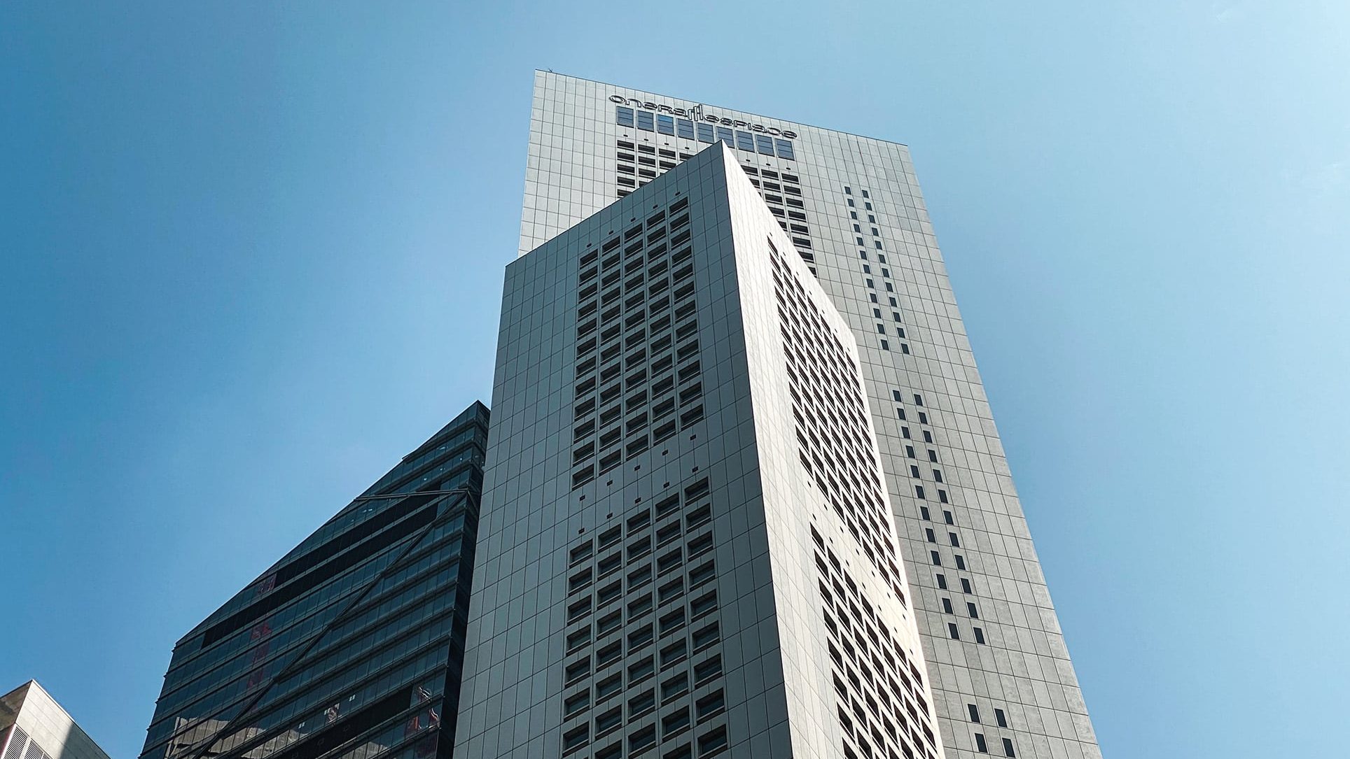 Tall commercial buildings with glass and panelled façades against a clear blue sky