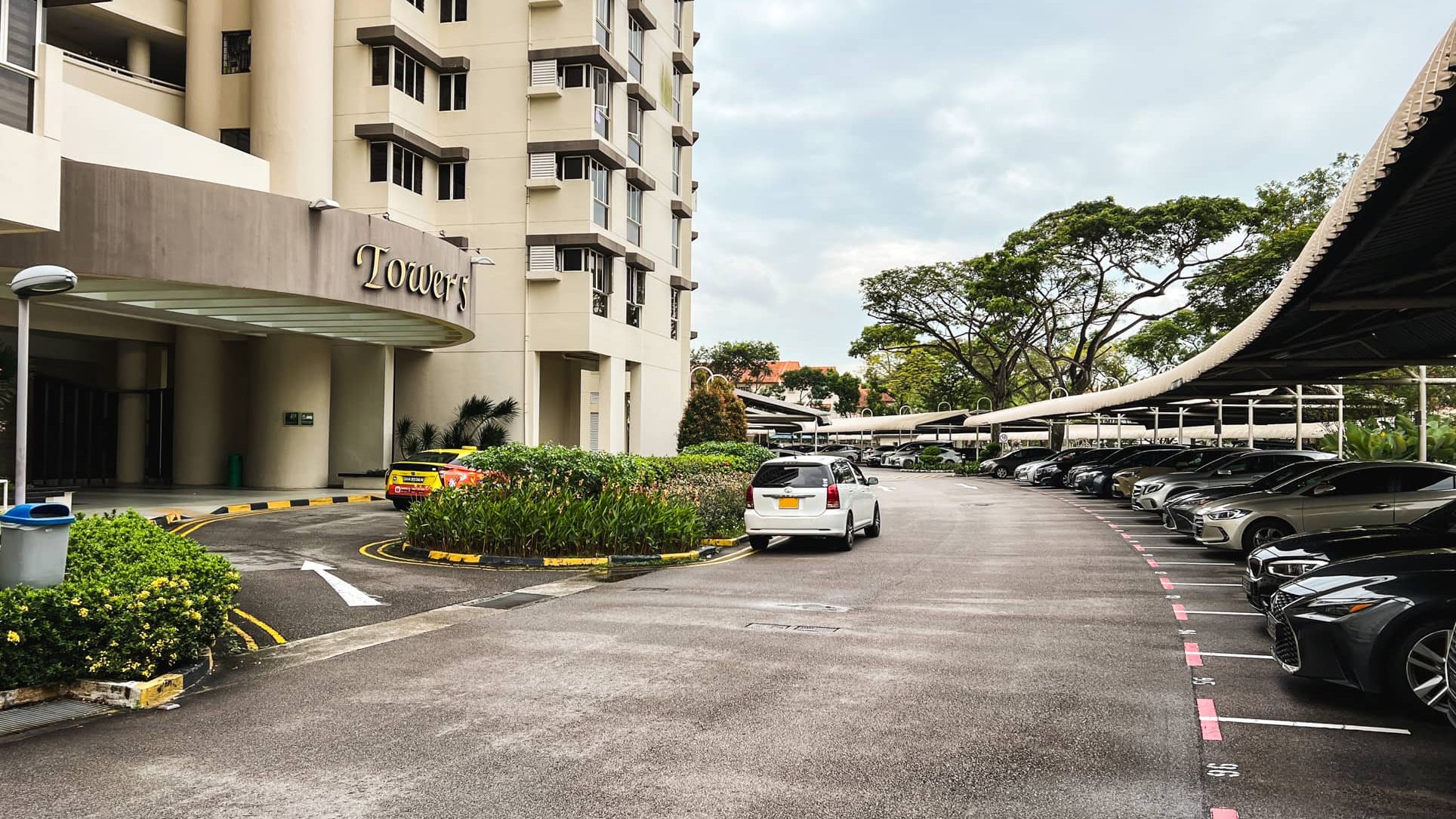 Bullion Park apartment block entrance with curved driveway, covered car park and parked cars on the right