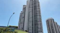 Tall residential apartment blocks with balconies under clear blue sky and a street lamp in the foreground