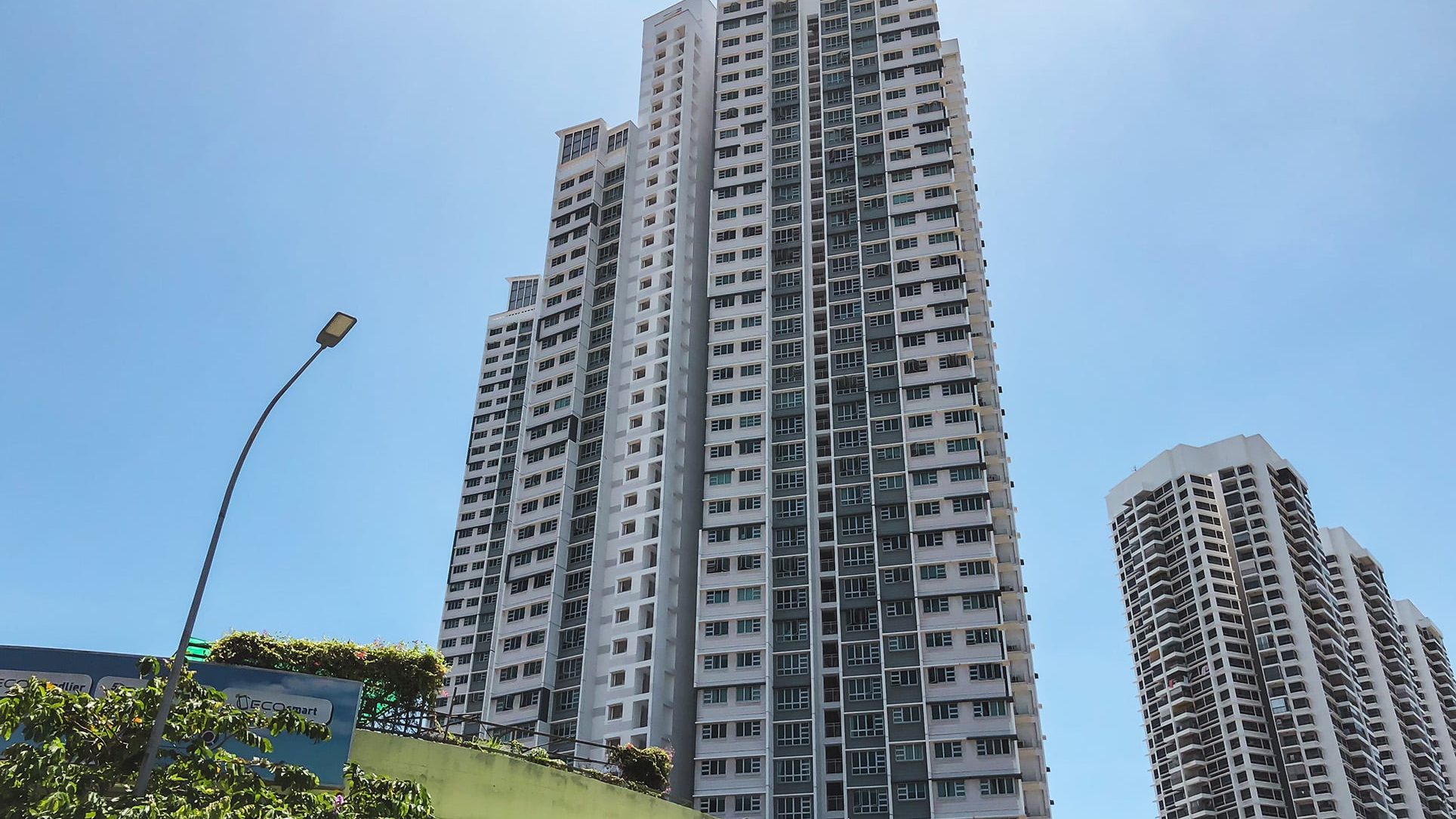 Tall residential apartment blocks with balconies under clear blue sky and a street lamp in the foreground