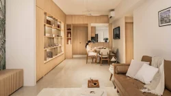 Living and dining area with wooden cabinetry, shelves, dining table, and brown sofa with cushions and throw blanket