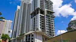 Tall residential apartment blocks with balconies under a bright blue sky with scattered clouds