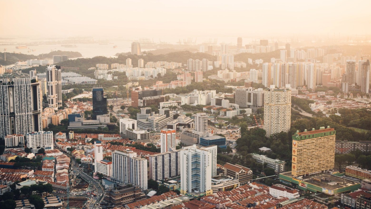 Dense urban area with a mix of high-rise apartments, HDB blocks, and low-rise houses under hazy sky