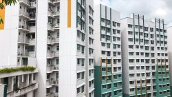 Woodlands Glen apartment blocks with white and teal façades and open windows under a cloudy sky