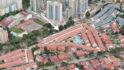 Aerial view of terraced houses with red roofs outlined and pointed to by a white arrow among high-rise apartments and trees