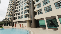 Apartment blocks with large windows adjacent to a curved swimming pool and paved poolside area