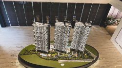 Architectural model of three high-rise residential blocks with surrounding landscaping and amenities on display table