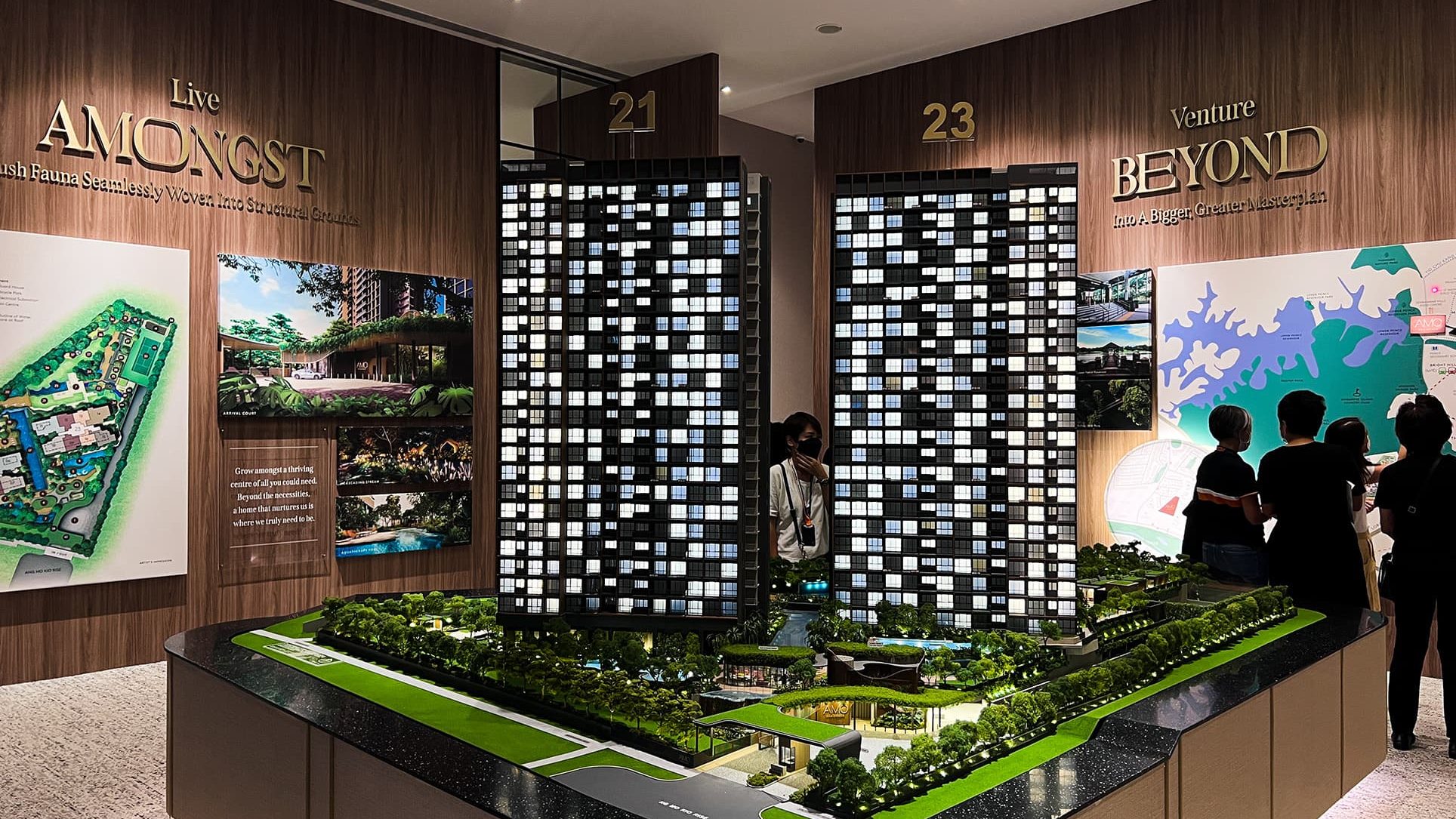 Architectural model of Amo Residence with two residential blocks numbered 21 and 23 displayed indoors with visitors nearby