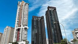Tall residential towers with modern balcony designs against a partly cloudy blue sky