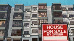 Block of apartments with air conditioners on balconies and a large house for sale sign in foreground