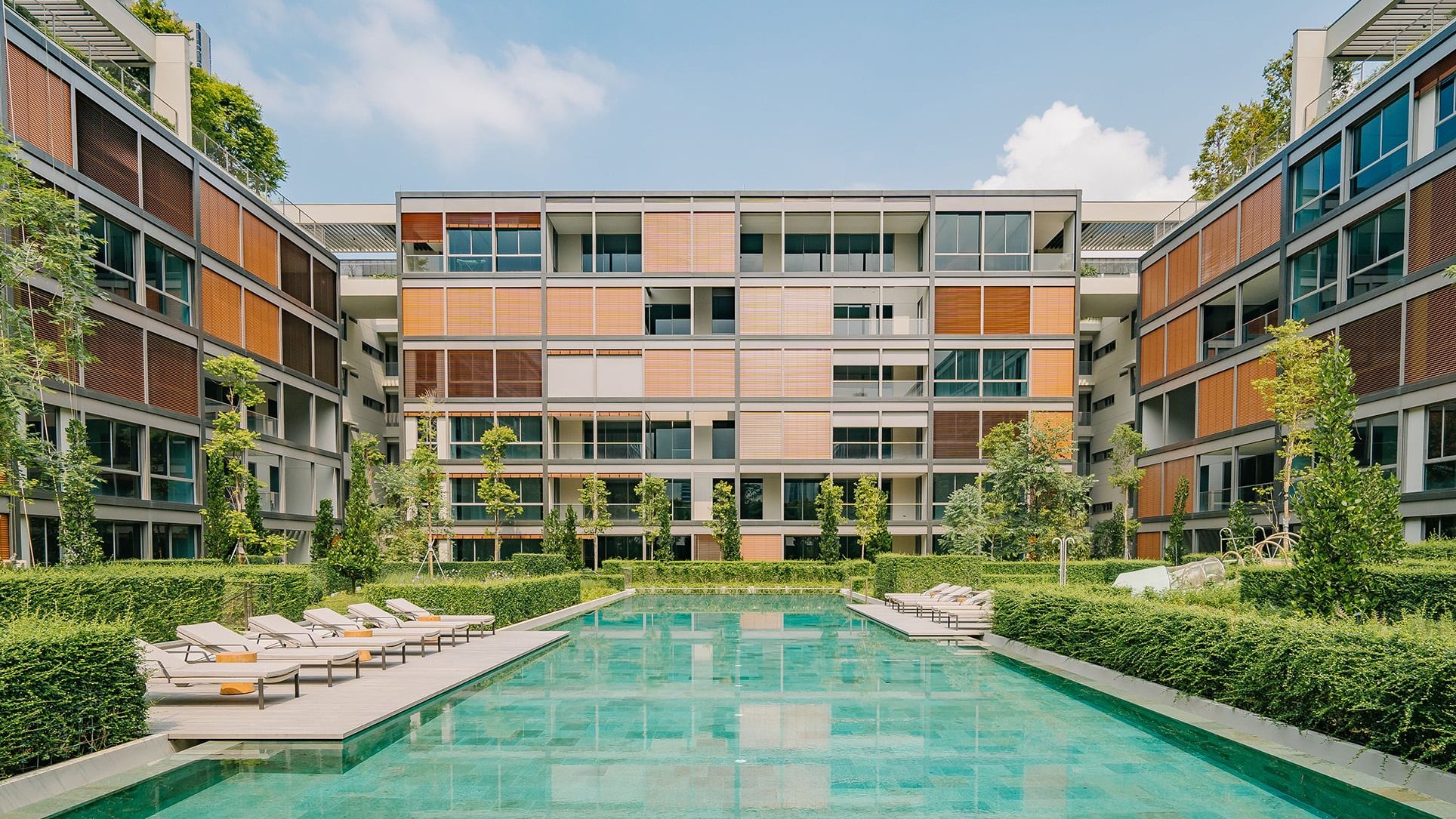 Meyer House apartment blocks with swimming pool, sun loungers, and landscaped greenery under blue sky