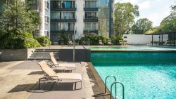 Swimming pool and poolside recliners at The Levelz apartment blocks with greenery and balconies visible