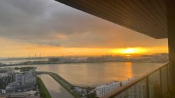 Sunset over industrial buildings, waterway and residential blocks seen from high-rise balcony
