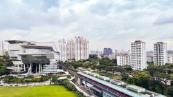 The colourful HDB blocks in Bukit Merah rise behind the modern building of the Redhill MRT station with green trees nearby