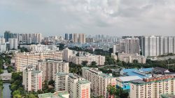 High-rise HDB residential blocks with greenery and a canal under cloudy sky