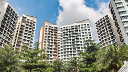 Hougang Capeview residential apartment blocks with brown patterned facades against a blue sky and greenery in front