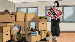 Woman standing in a room with packed cardboard boxes holding a sold property sign