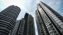 Tall modern residential apartment blocks with glass windows under a partly cloudy sky