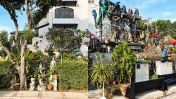 Two houses with lush gardens, many animal statues, and a Green Lantern figure on one balcony