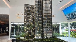 Scale model of The Orie residential blocks in a showroom with a digital screen and garden views outside