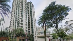 Residential high-rise apartment blocks surrounded by trees and palm trees under cloudy sky