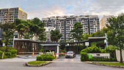 Entrance to The Rainforest EC with a car at the guarded gate and residential blocks surrounded by trees