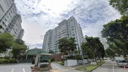 Residential apartment blocks with a guardhouse and driveway, surrounded by trees under a partly cloudy sky