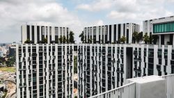 Two high-rise apartment blocks connected by a sky bridge with trees and plants on top