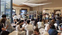 People gathered in a sales gallery at Lucerne Grand discussing and viewing property models and plans