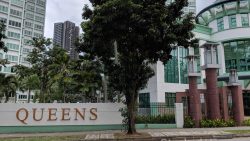 Signboard for Queens condominium with tall residential blocks and greenery around the entrance