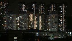 Housing blocks with numerous illuminated windows against a night sky