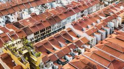 Terracotta roofed traditional shophouses clustered together with some modern air conditioners and rooftop plants
