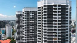 Tall white residential apartment blocks with balconies under a clear blue sky