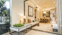 Living and dining area with beige sofas, dining table, plants, wall art, and a large window at Verdale